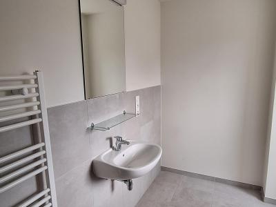 Badkamer met één lavabo, spiegel met verlichting, handdoekradiator, witte muren en grijze vloer