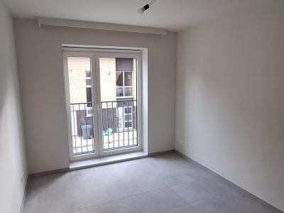 Slaapkamer met één groot raam, witte muren en grijze vloer